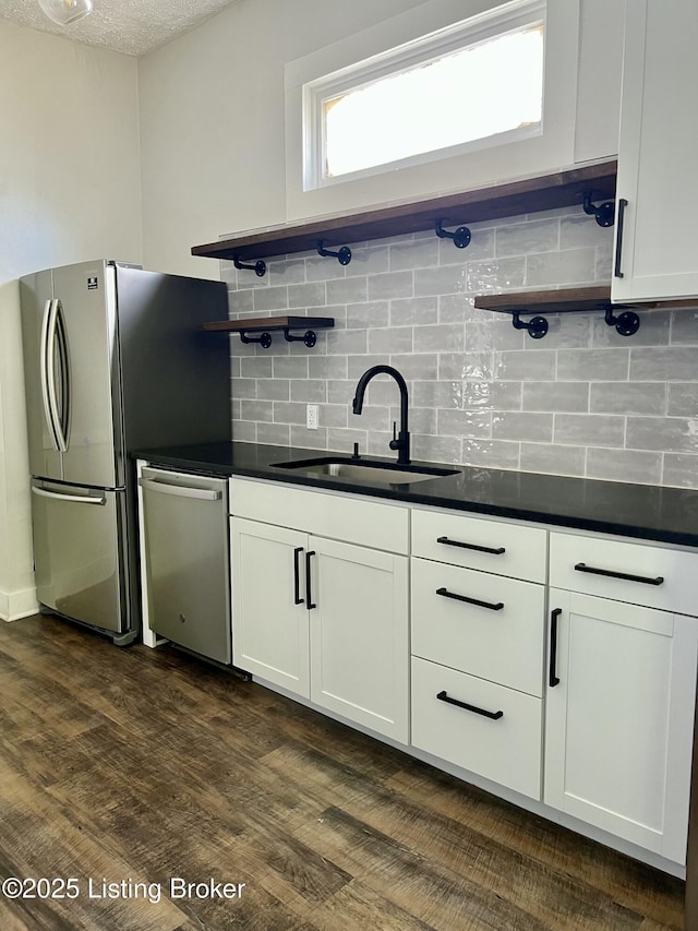 kitchen with backsplash, white cabinetry, sink, and stainless steel appliances