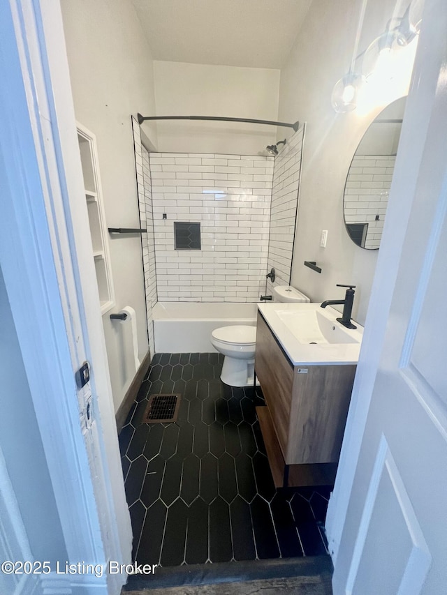 full bathroom with tiled shower / bath, tile patterned flooring, vanity, and toilet