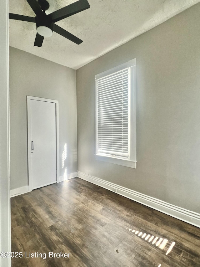 unfurnished room featuring a textured ceiling, baseboards, and wood finished floors