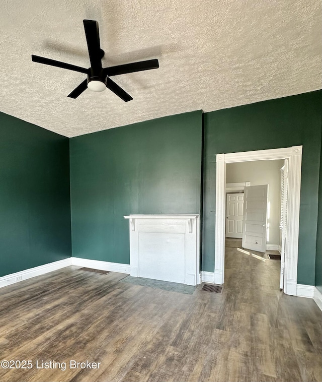 spare room with ceiling fan, a textured ceiling, wood finished floors, and baseboards