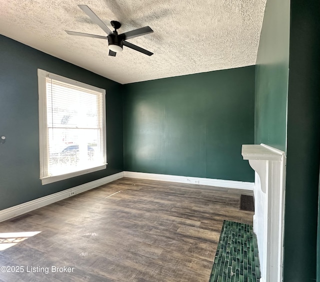 unfurnished room featuring baseboards, visible vents, a ceiling fan, wood finished floors, and a textured ceiling