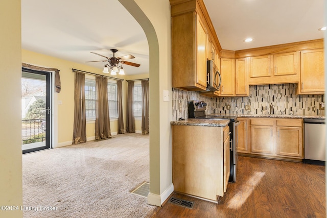 kitchen featuring ceiling fan, light stone countertops, dark colored carpet, tasteful backsplash, and appliances with stainless steel finishes