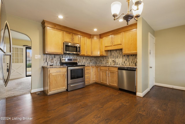 kitchen featuring dark wood-type flooring, an inviting chandelier, light stone counters, backsplash, and appliances with stainless steel finishes