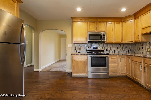 kitchen with decorative backsplash, appliances with stainless steel finishes, stone countertops, and dark wood-type flooring