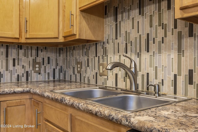 kitchen featuring backsplash, dark stone countertops, and sink