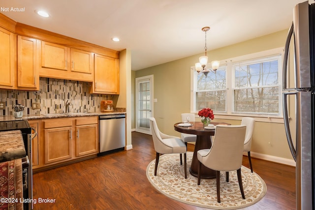 kitchen with sink, dark wood-type flooring, stainless steel appliances, backsplash, and a chandelier