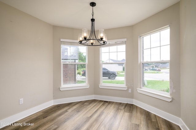 unfurnished dining area with wood-type flooring and a chandelier