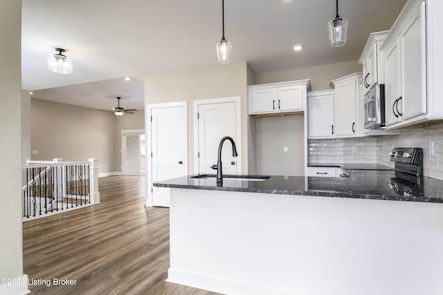 kitchen featuring kitchen peninsula, sink, black range, white cabinetry, and hanging light fixtures