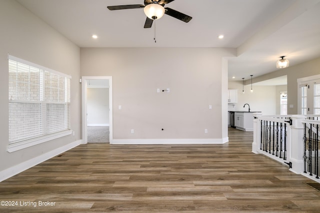 unfurnished living room featuring hardwood / wood-style flooring, ceiling fan, and sink