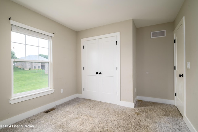 unfurnished bedroom featuring light colored carpet, multiple windows, and a closet