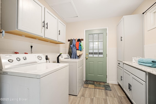 clothes washing area with washing machine and dryer and cabinets