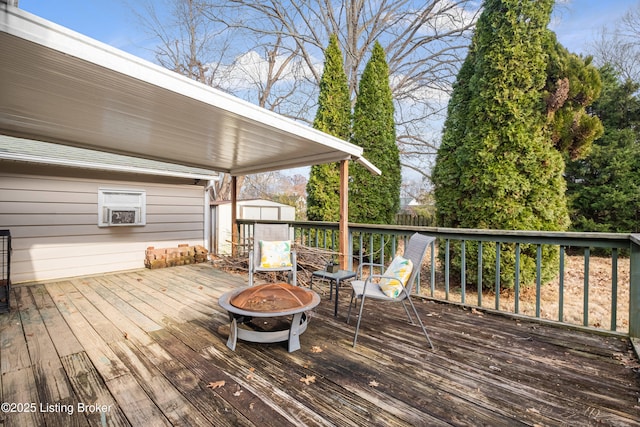 wooden deck featuring a storage shed and an outdoor fire pit