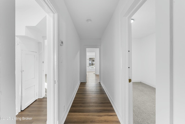 corridor with baseboards and dark wood finished floors