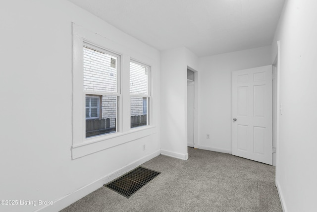 unfurnished room featuring visible vents, carpet floors, and baseboards