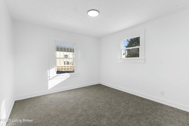 unfurnished room with baseboards and dark colored carpet