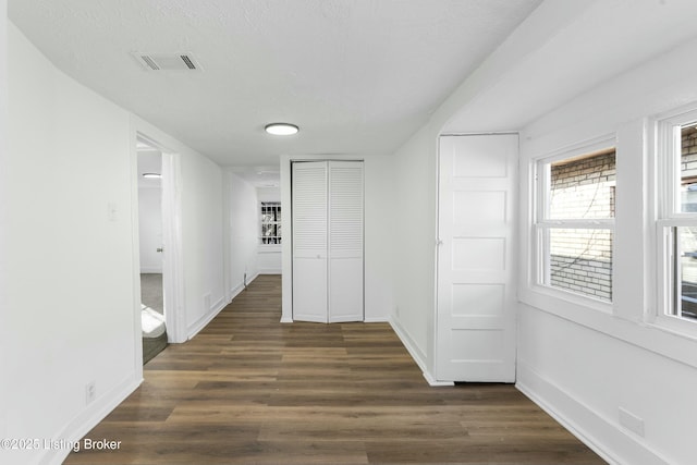 corridor with visible vents, a textured ceiling, dark wood-type flooring, and baseboards