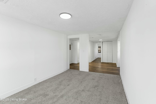 unfurnished room with dark carpet and a textured ceiling