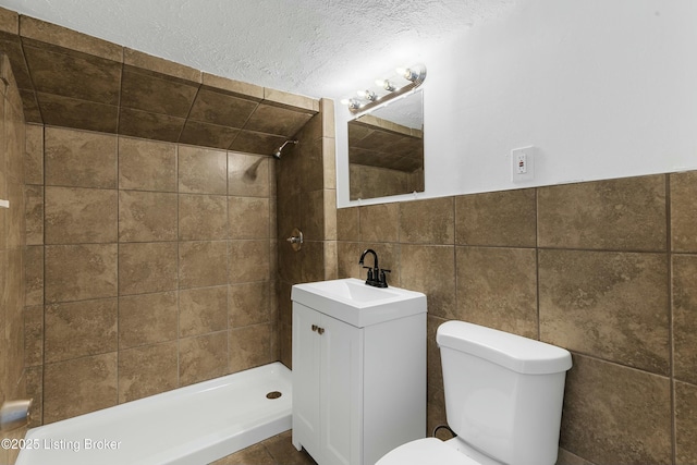 bathroom featuring tile walls, tiled shower, vanity, a textured ceiling, and toilet