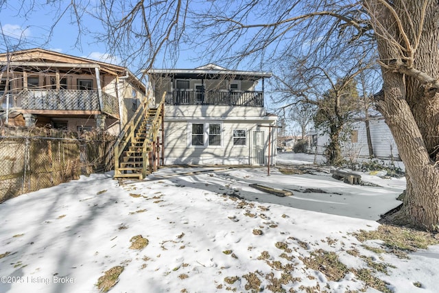 snow covered rear of property featuring a balcony