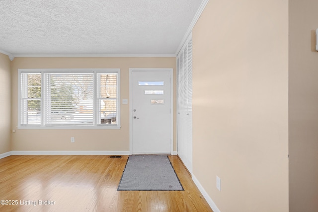 entrance foyer with a textured ceiling, light hardwood / wood-style floors, and crown molding