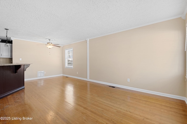 unfurnished living room featuring a textured ceiling, light hardwood / wood-style floors, and crown molding