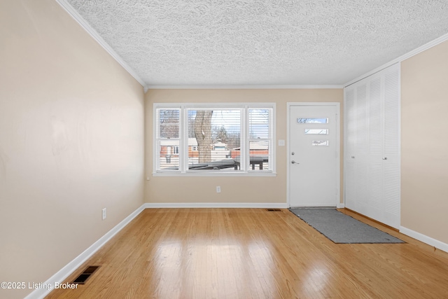 entryway featuring crown molding, hardwood / wood-style floors, and a textured ceiling