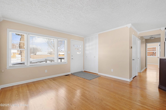 foyer with light hardwood / wood-style flooring, a textured ceiling, and ornamental molding