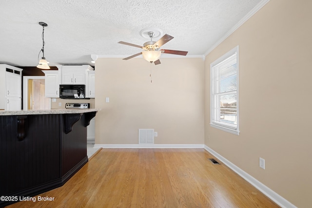 kitchen with crown molding, light wood-type flooring, decorative light fixtures, a kitchen bar, and white cabinetry