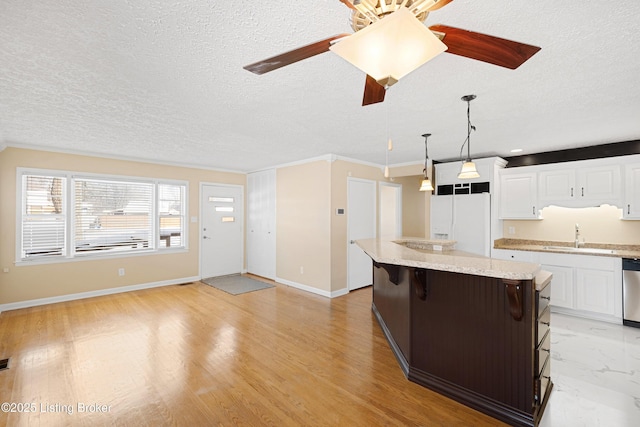 kitchen featuring sink, a kitchen island, white refrigerator with ice dispenser, a breakfast bar area, and white cabinets