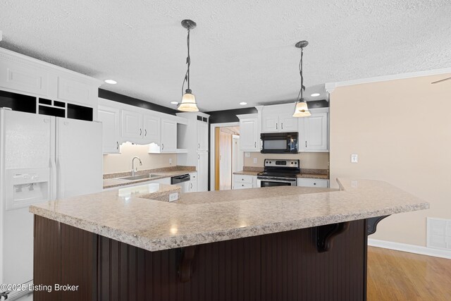 kitchen with white cabinets, hanging light fixtures, a textured ceiling, appliances with stainless steel finishes, and a large island