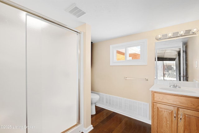 bathroom with hardwood / wood-style floors, vanity, toilet, and an enclosed shower