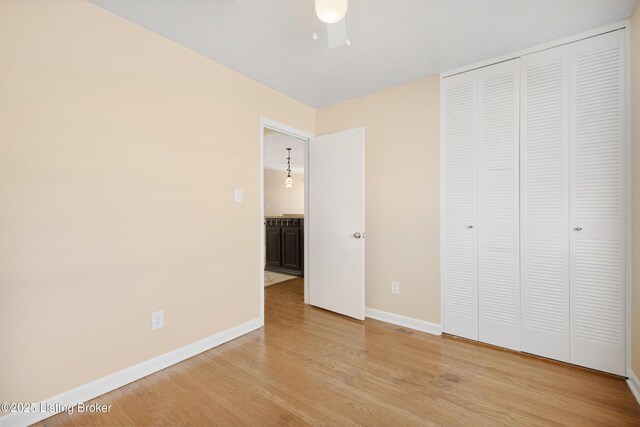 unfurnished bedroom featuring ceiling fan, a closet, and light wood-type flooring