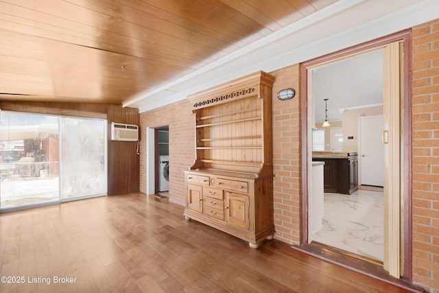 unfurnished living room with plenty of natural light, washer / dryer, wooden ceiling, and a wall unit AC