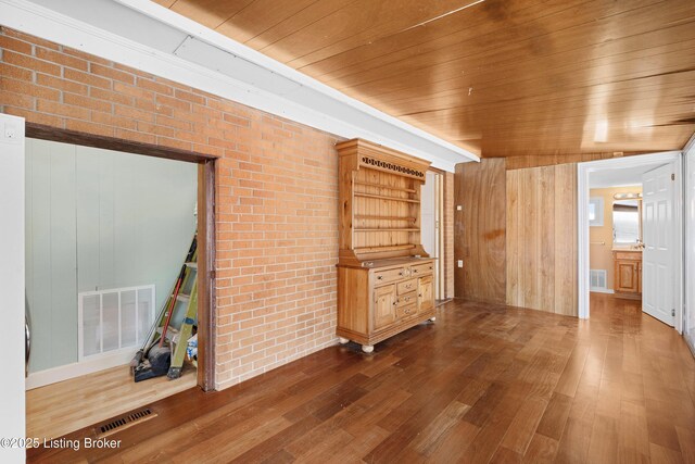 unfurnished living room with hardwood / wood-style floors, wooden ceiling, wooden walls, and brick wall