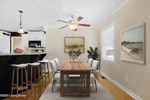 dining area with crown molding, ceiling fan, a textured ceiling, and hardwood / wood-style flooring