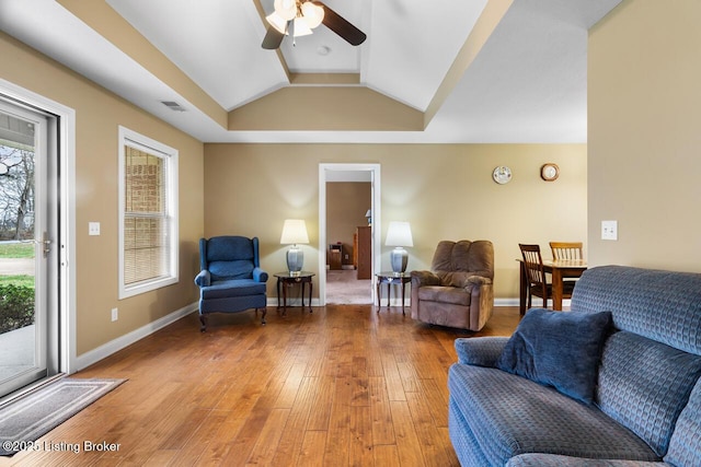 living room with hardwood / wood-style floors, ceiling fan, a tray ceiling, and vaulted ceiling