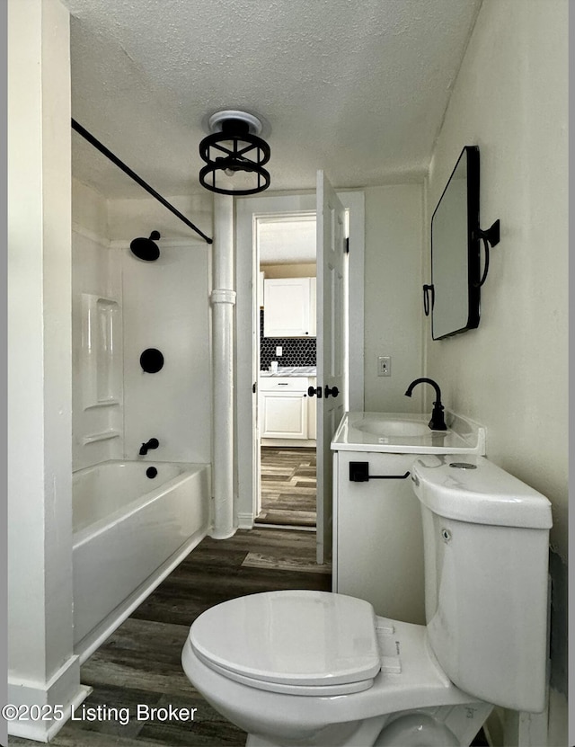 full bathroom with backsplash, bathtub / shower combination, hardwood / wood-style flooring, toilet, and a textured ceiling