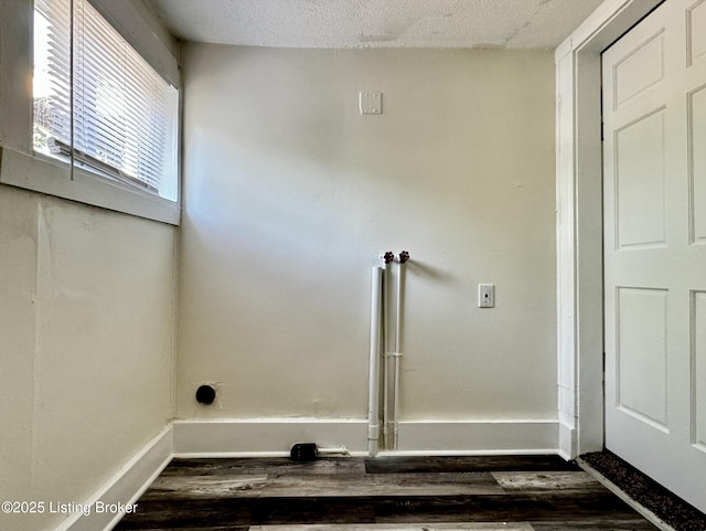 laundry area with a textured ceiling and dark wood-type flooring