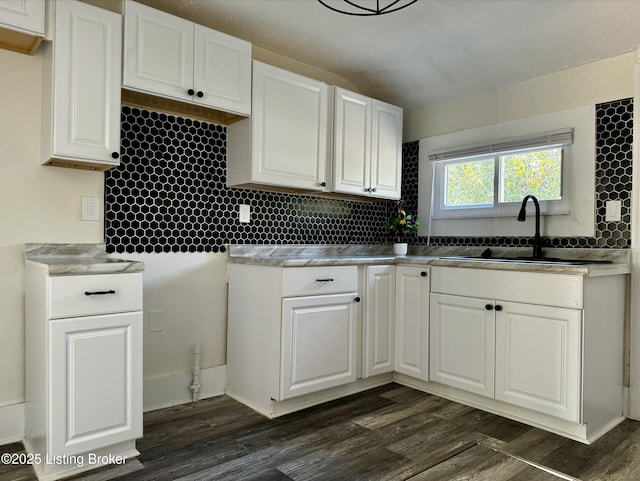 kitchen featuring tasteful backsplash, white cabinetry, sink, and dark wood-type flooring