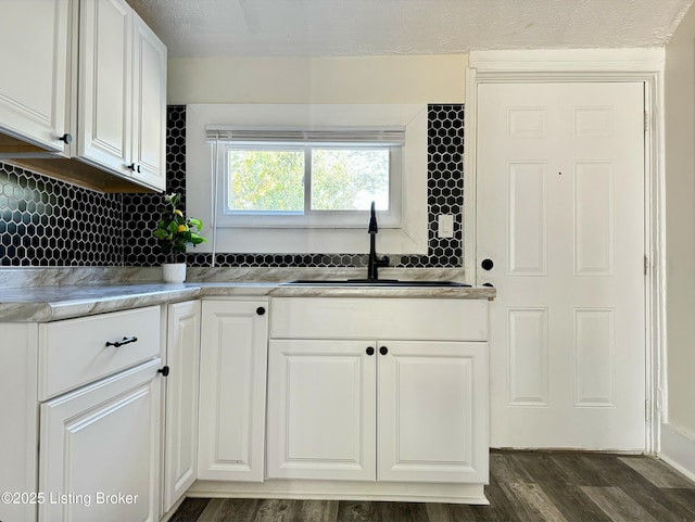 kitchen featuring backsplash, white cabinetry, sink, and dark wood-type flooring