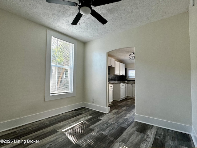 interior space with a textured ceiling, ceiling fan, and dark wood-type flooring