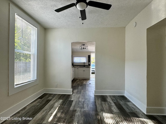 unfurnished room with a wealth of natural light, dark hardwood / wood-style flooring, ceiling fan, and sink