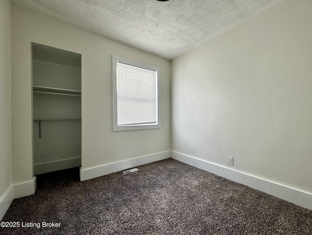 unfurnished bedroom featuring dark carpet and a textured ceiling