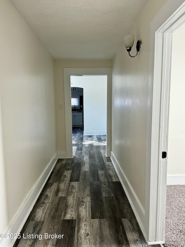 corridor featuring dark hardwood / wood-style flooring and a textured ceiling