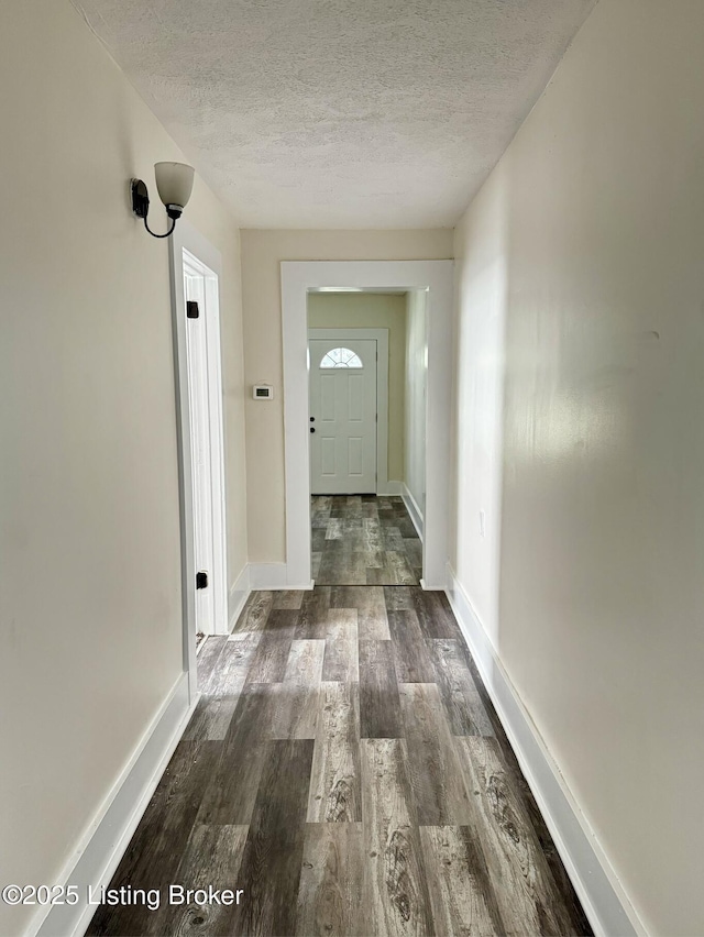 hallway with a textured ceiling and dark wood-type flooring