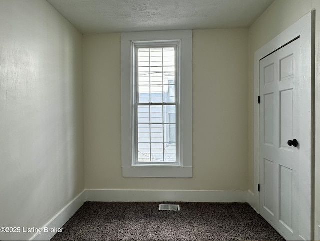 unfurnished room with carpet flooring and a textured ceiling