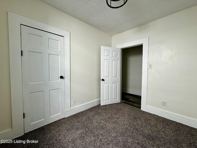 unfurnished bedroom featuring dark carpet and a textured ceiling