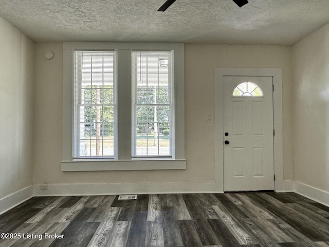 entrance foyer featuring a textured ceiling, dark hardwood / wood-style flooring, ceiling fan, and a healthy amount of sunlight