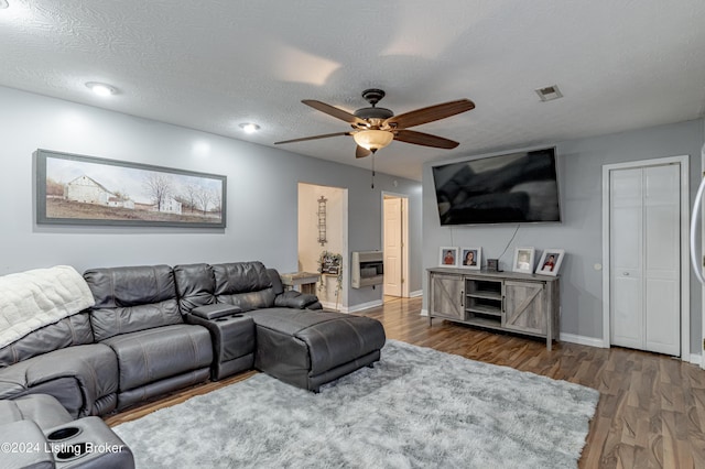 living room with heating unit, ceiling fan, dark hardwood / wood-style flooring, and a textured ceiling