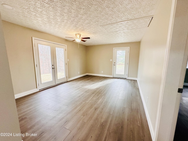 spare room featuring a textured ceiling, ceiling fan, light hardwood / wood-style flooring, and french doors